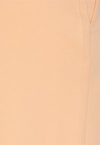 Tecido bege com uma textura suave e um padrão de trama diagonal subtil. Costura visível ao longo do lado cria linhas estruturadas.