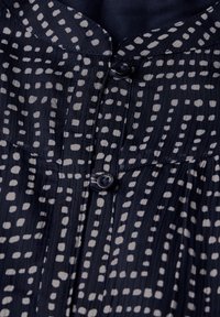 Marineblause mit Muster in Blau und weißen Punkten, mit Knopfverschluss und Falten-Design. Weicher, leichter Stoff mit glatter Textur.