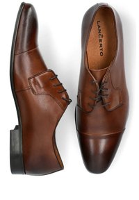 Brązowe skórzane buty wizytowe o eleganckim designie, z gładkim wykończeniem, sznurowanym przodem i lekko spiczastym noskiem. Nazwa marki wewnątrz.