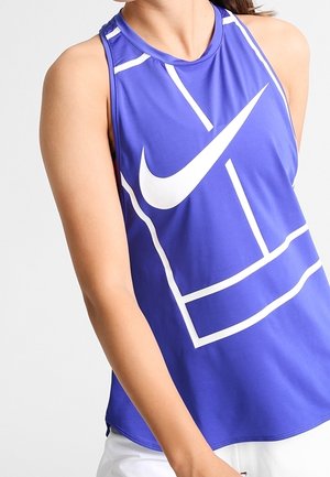 Femme portant un débardeur de sport bleu avec des lignes géométriques blanches et un grand logo blanc Nike swoosh à l'avant.