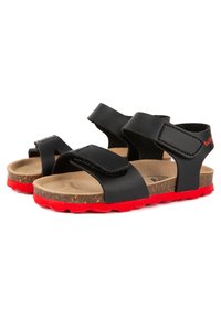 Sandales en cuir noir avec semelle en liège, semelle en caoutchouc rouge et bandes ajustables à crochets et boucles. Présentent une surface texturée pour une meilleure adhérence.