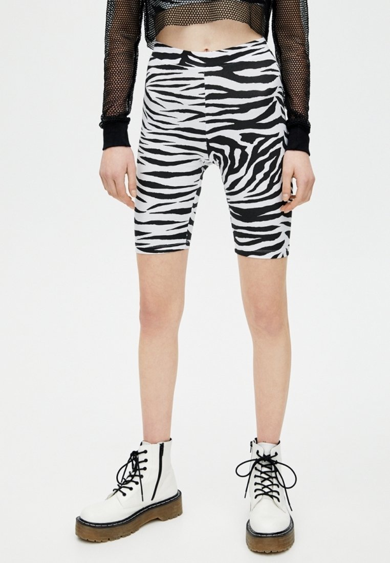 Zwart-wit zebra print fietsbroekjes van rekbaar materiaal, met een hoge taille en een aansluitende pasvorm, die net boven de knie eindigen.
