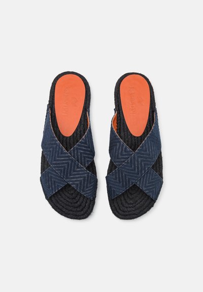 Sötétkék, slip-on stílusú szandálok, keresztbe rakott heringmintás szövetpántokkal, fekete fonott talppal és narancssárga párnázott talpbetéttel.