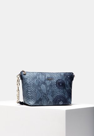 Petit sac clutch bleu avec texture effet peau de serpent et motifs circulaires, doté d'une chaîne dorée, présenté sur un piédestal blanc sur fond gris.