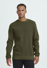 Maglione lavorato a maglia verde oliva con maniche lunghe, scollo rotondo, polsini e orlo a coste, realizzato in tessuto testurizzato.