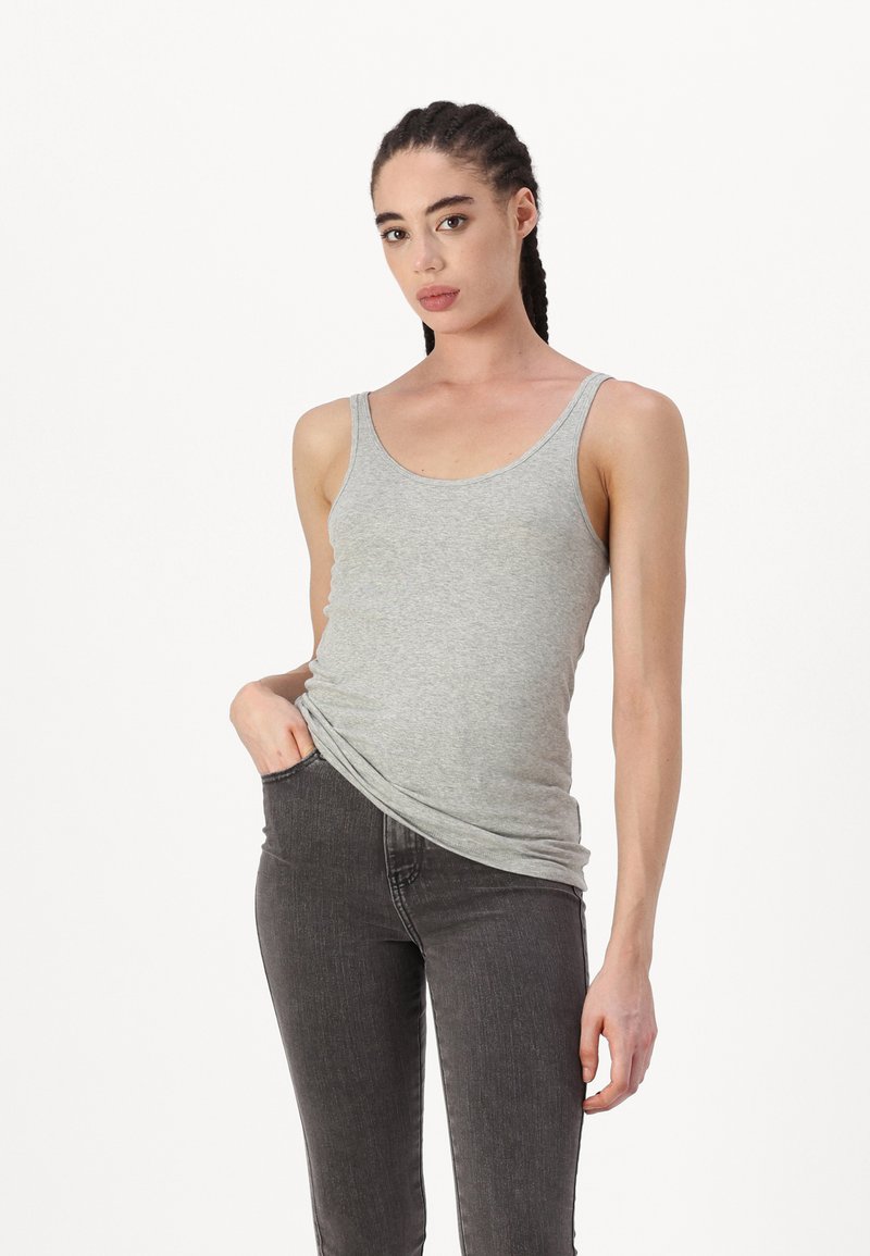 Top de tirantes gris de algodón con escote redondo y tirantes finos, combinado con unos pantalones ajustados oscuros. Textura suave, diseño simple, corte ajustado.