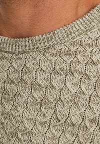 Pull en tricot beige clair avec un motif en losanges texturé, un col côtelé et un subtil contraste de couleur de fil.