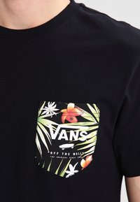 Černé bavlněné tričko s barevným designem kapsy s tropickými květinovými vzory a logem "VANS OFF THE WALL" v bílé barvě.