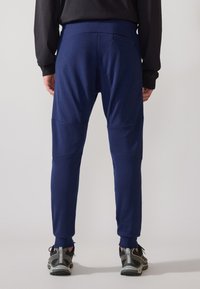 Marineblå joggebukser med en kroppsnær passform, som har et strikk i livet og smale ben, laget av et mykt, elastisk stoff med minimale sømmer.