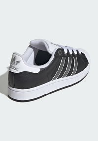 Black leather sneakers with white accents, featuring three stripe design, rubber sole, round toe, and padded collar for comfort.