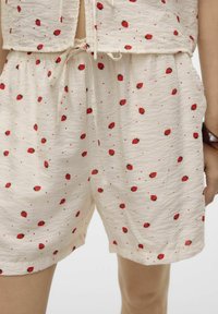 Lichte,roomkleurige shorts met een gestructureerde stof, voorzien van een rode aardbeienprint en een trekkoord in de taille. Inclusief zijzakken.