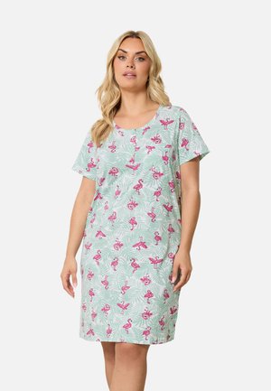 Nainen käyttää vaaleanvihreäpohjaista, polvipituista mekkoa, jossa on vaaleanpunaisia flamingokuvioita.