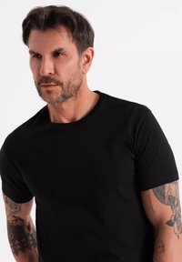 Černé tričko s kulatým výstřihem vyrobené z bavlněné směsi, s hladkou texturou. Bez viditelných vzorů, s krátkými rukávy a volným střihem.