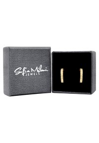 Guldtonade örhängen med en texturerad yta som visas i en grå smyckeslåda klädd med svart sammet, med vit logotext.