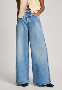 Gai zils platās kājas denim džinsi ar augstu jostasvietu, ar klasisku 5 kabatu dizainu un smalku whakapirāšanu tekstūras pievienošanai.