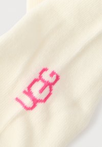 Κάλτσα από βαμβάκι κρεμ χρώματος με έντονο ροζ λογότυπο "yes", λεία υφή και ριμπ σχέδιο για επιπλέον άνεση.