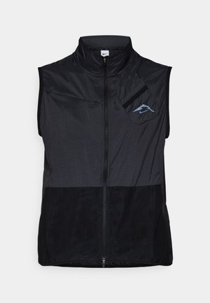 Svart ermeløs vest med høy krage, laget av lett stoff. Har glidelås foran og brystlomme på venstre side med blå logo.