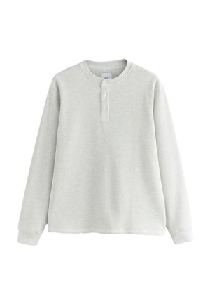 Hellgraues Langarm-Waffle-Knit-Henley-Shirt mit drei Knöpfen und gerippten Bündchen, flach auf weißem Hintergrund ausgelegt.