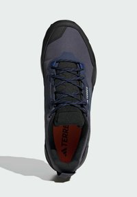 Tmavomodrá turistická obuv s textúrovaným povrchom, čiernymi akcentmi a kontrastnými šnúrkami. Obsahuje polstrovaný interiér s viditeľným brandingom.