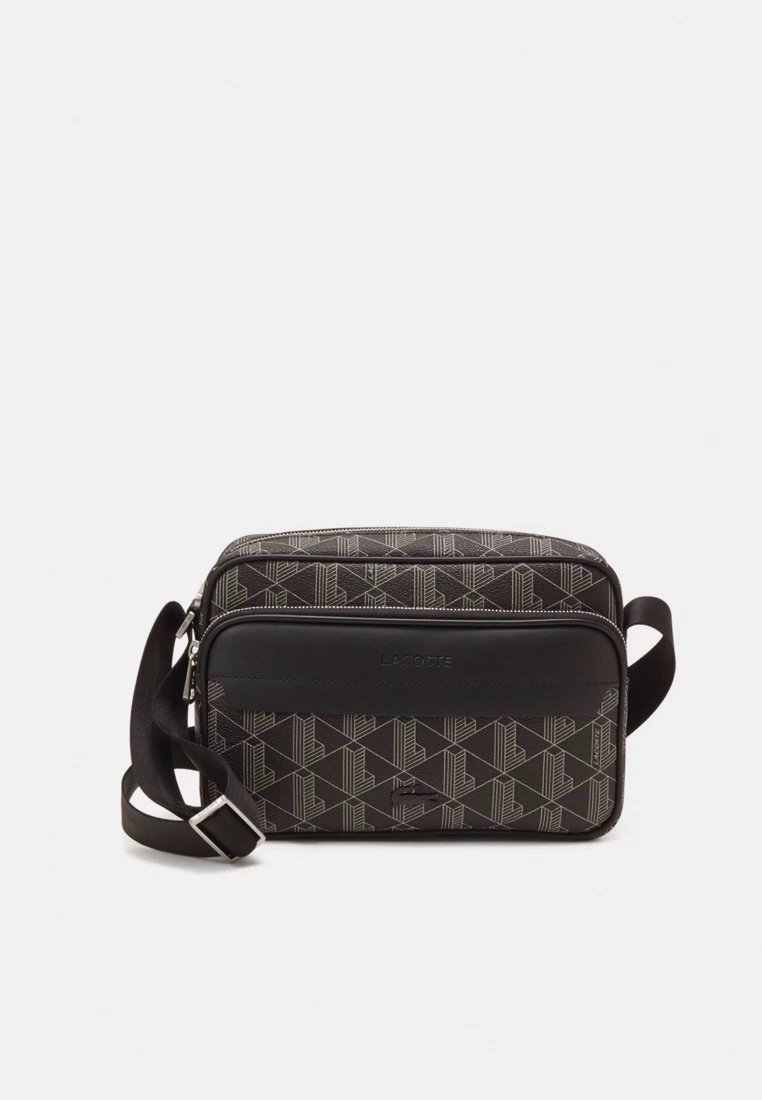 Sac bandoulière noir et gris avec motif géométrique, accents en cuir, sangle ajustable et une poche zippée à l'avant avec détail du logo.