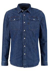 Chemise en denim bleu foncé à manches longues, avec col, fermeture boutonnée sur le devant et deux poches poitrine à rabat et bouton.