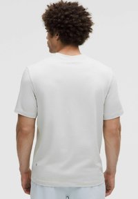 Svetlošedé tričko s krátkym rukávom vyrobené z mäkkého materiálu. Má okrúhly výstrih, voľný strih a jemné logo blízko lemu.