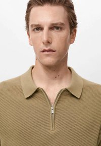 Khaki rits polo trui met een gestructureerd breipatroon, voorzien van een kraag en een korte rits. Eenvoudige en schone esthetiek.