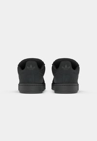 Svarta sneakers med övre del av mocka, rund tå, vadderad krage och strukturerad gummisula. Har en diskret präglad logga på hälen.