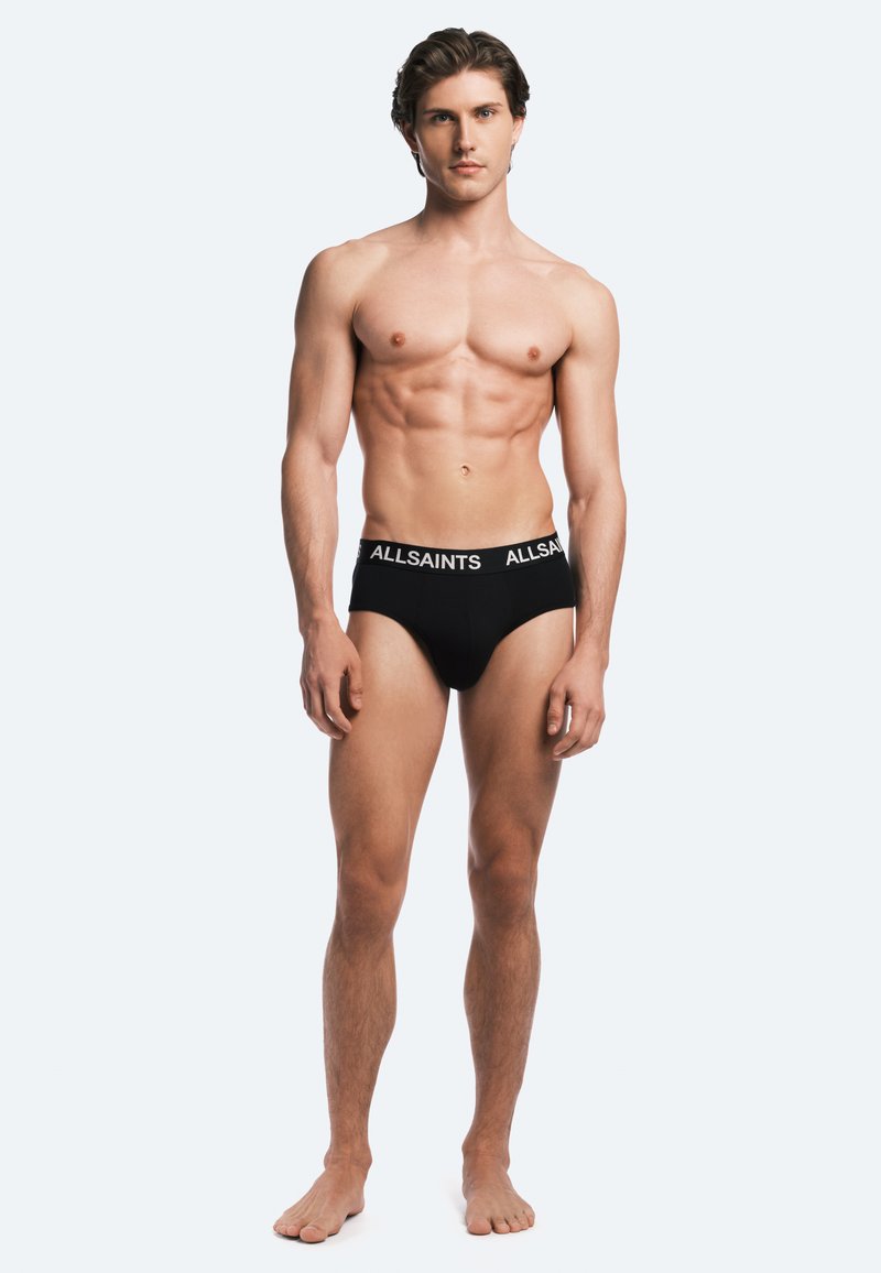 Black cotton brief with elastic waistband featuring "ALLSAINTS" logo. Simple design and form-fitting shape, smooth texture.
