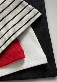 Cztery prążkowane bawełniane T-shirty w kolorze czarnym, białym, czerwonym i kremowym w czarne paski, z okrągłymi dekoltami i wykończonymi brzegami.