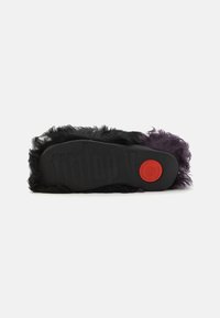 Svart och lila fluffig slide-sandal med en texturerad gummisula. Har en framträdande röd cirkulär logotyp och en dämpad fotbädd.