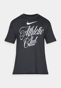 T-shirt en coton noir avec texte graphique blanc "Athletic Club" et logo Nike sur la poitrine ; manches courtes, coupe classique.