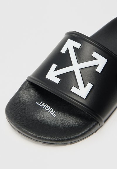 Sandalo slide nero con una fascia ampia e un prominente logo a forma di freccia bianca. Il plantare testurizzato offre grip, con la scritta "RIGHT." stampata sotto.