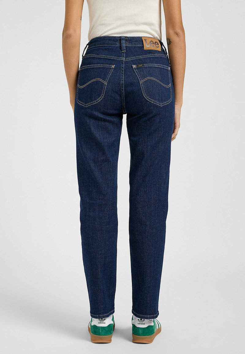 Granatowe dżinsy o prostym kroju, z wyszytymi detalami i dwoma tylnymi kieszeniami. Widoczna metka marki Lee na pasku.