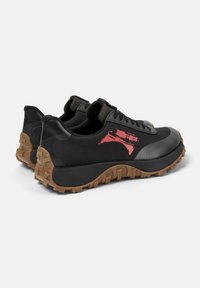 Sneaker neri con upper testurizzato, punta gommata e una grafica rossa. Presentano una suola robusta color beige con lugs prominenti per una migliore aderenza.
