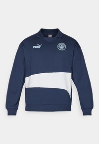 Hanorac bleumarin cu o dunga orizontală albă, guler și logo. Fabricat dintr-un amestec de bumbac, prezintă manșete și tiv cu fire răsucite. Design sportiv.