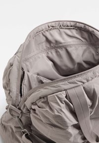 Harmaa nylonnauhalaukku, jossa on kiristetty yläosa, sisätasku ja OYSHO-logo. Pehmeä koostumus, rypytetty muotoilu ja säädettävä hihna.