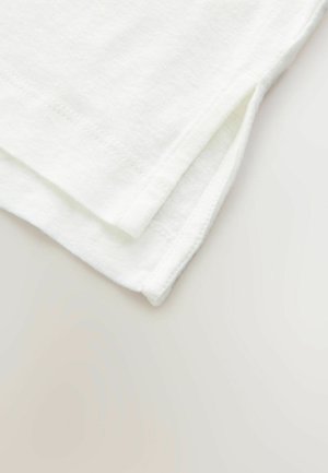 Tela de algodón blanca doblada cuidadosamente, con un borde limpio y pequeñas aberturas en el dobladillo, mostrando una textura suave.