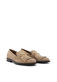 Beige suède loafers met franje, gouden hardware-accenten en een lage zwarte zool. Zorgvuldig afgewerkt met een klassieke uitstraling.