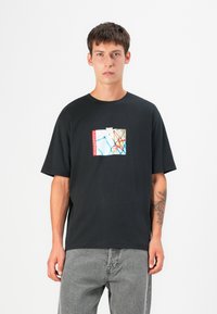 Black cotton t-shirt featuring a graphic print with blue, white, and red accents. It has short sleeves and a loose fit.