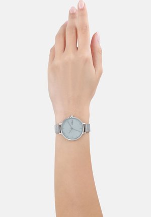 Silbernes Mesh-Armband-Uhr mit einem runden, hellblauen Ziffernblatt. Verfügt über minimalistische Stundenmarkierungen und eine einfache Krone auf der rechten Seite.