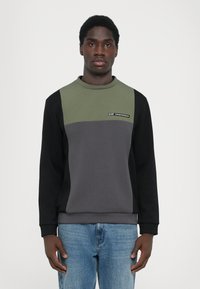Sweatshirt colorat în gri și verde, cu mâneci negre, având un guler rotund și un detaliu mic cu logo pe partea din față.