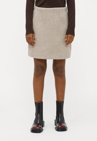 Hea hall villane mini-seelik, millel on kaks küljetaskut, koos mustade pahkluudega saapastega, millel on punane aktsent, näidatud taljast allapoole.