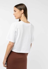 Witte cropped t-shirt van katoen, met korte mouwen en een ronde halslijn. De achterkant is glad met een eenvoudige textuur.