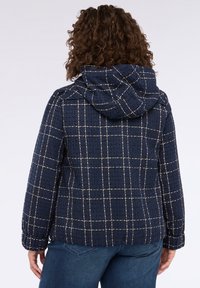 Marinblå, huva jacka med en strukturerad yta och ett guldprickigt mönster. Har en avslappnad passform och elastiska ärmslut.