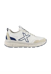 Zapatilla deportiva blanca con acentos en azul marino, con una suela chunky con un patrón moteado, parte superior de cuero suave y detalles laterales perforados.