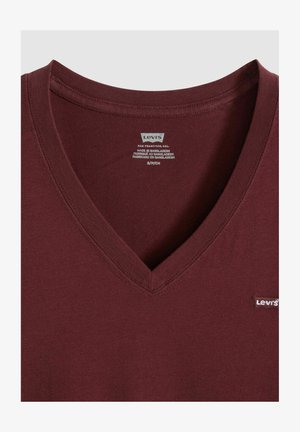 Dunkelrotes V-Ausschnitt-T-Shirt mit weicher Textur, das auf der linken Seite ein kleines weißes Levi's-Logo und am Kragen ein Pflegeetikett zeigt.