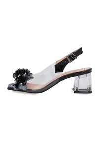 Clear heeled sandal with a transparent upper, black floral embellishment, and ankle strap. Square toe and 3-inch block heel.