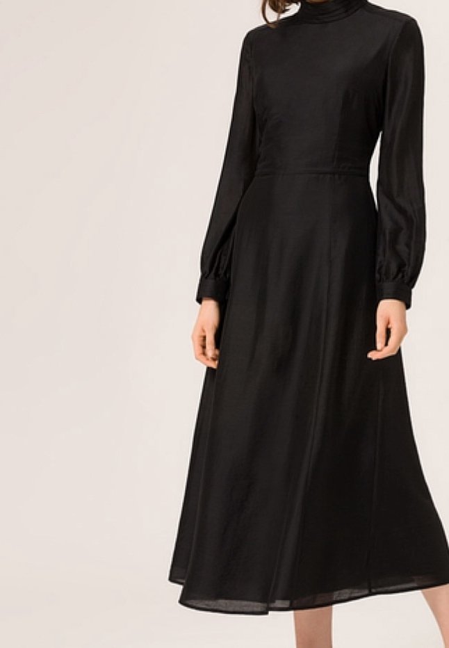 Robe longue noire en tissu lisse, dotée d'un col montant, de manches longues bouffantes et d'une jupe fluide qui descend en dessous des genoux.