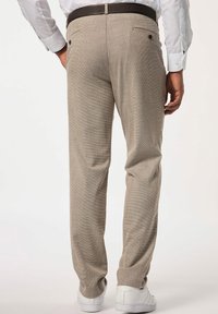 Beige gemusterte Hose mit geradem Bein, ausgestattet mit Gesäßtaschen und einem braunen Gürtel, kombiniert mit weißen Sneakern.